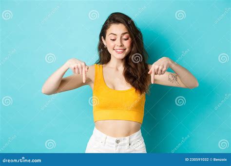 Portrait Of Stylish Natural Girl In Summer Crop Top Pointing And Looking Down With Dreamy Smile