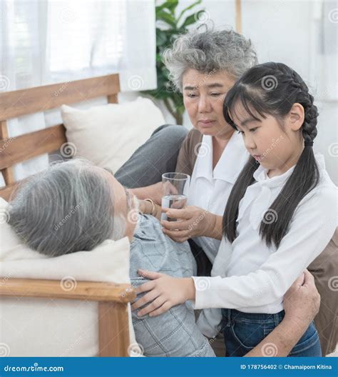 asian grandmother and granddaughter look after and take care grandfather give glass of water