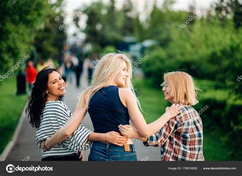 Três raparigas a divertirem se no parque do pôr do sol vista traseira