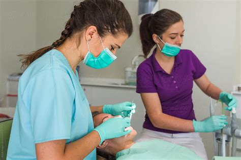 orthodontist assisted by nurse curing patient in dental office by stocksy contributor ibex