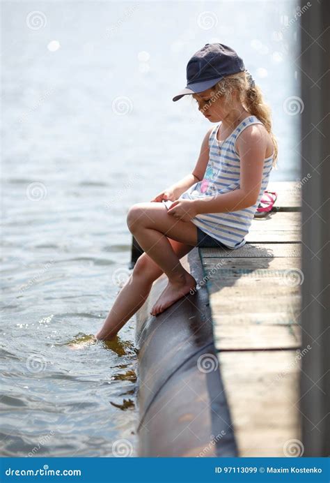 Bambina Che Si Siede Su Una Piattaforma Di Legno Dal Fiume O Dal Lago Mentre Spruzzando Acqua