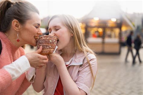 Happy Mother And Daughter At Fair In City Eating Trdelnik Stock Image
