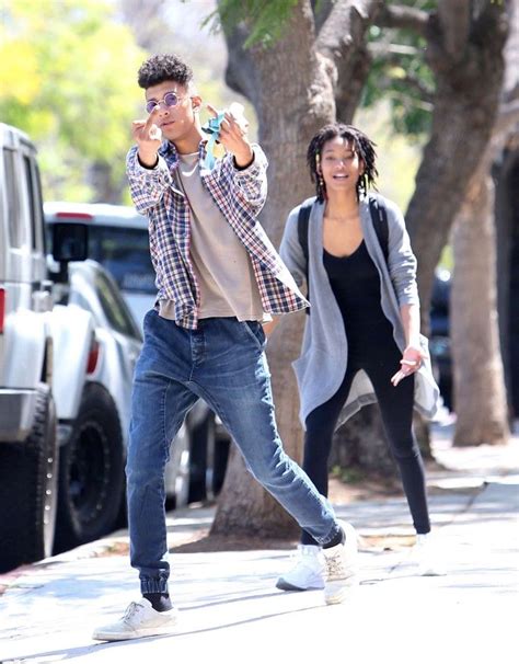 A Man And Woman Are Walking Down The Street While Talking On Their Cell