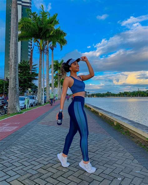 a woman in blue sports bra top and leggings standing on brick walkway next to water