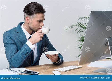 Young Businessman Drinking Coffee While Using Desktop Computer In