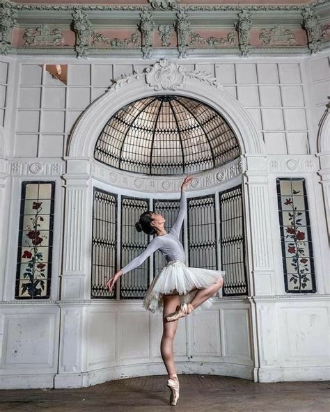 A Ballerina Is Posing In Front Of An Arched Window