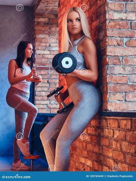 two sporty girls dressed in sportswear with barbells posing in a stock image image of adult