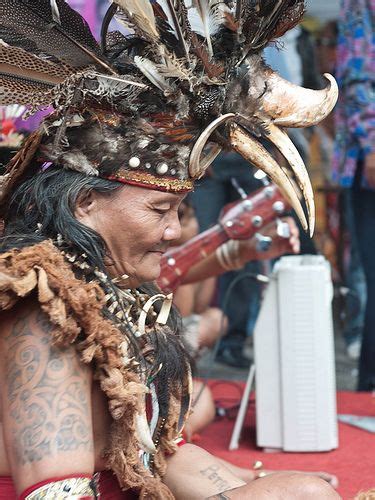 A Native American Man Sitting On The Ground With His Headdress Covered