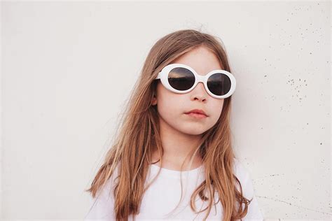 Young Girl Leaning Against Wall Outside Wearing Sunglasses Photograph