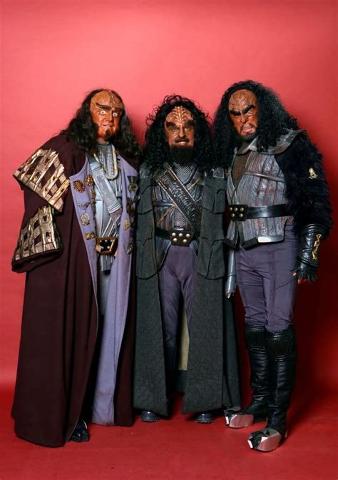 Three Men In Costumes Standing Next To Each Other