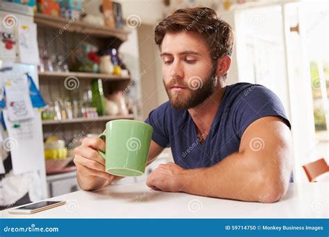 Young Man Sitting At Kitchen Table Drinking Coffee Stock Photo Image