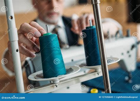 Cropped Image Of Senior Tailor Touching Spool Of Thread On Sewing