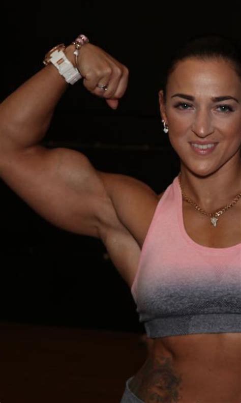 A Woman Flexing Her Muscles In A Pink And Grey Tank Top With Two Bracelets