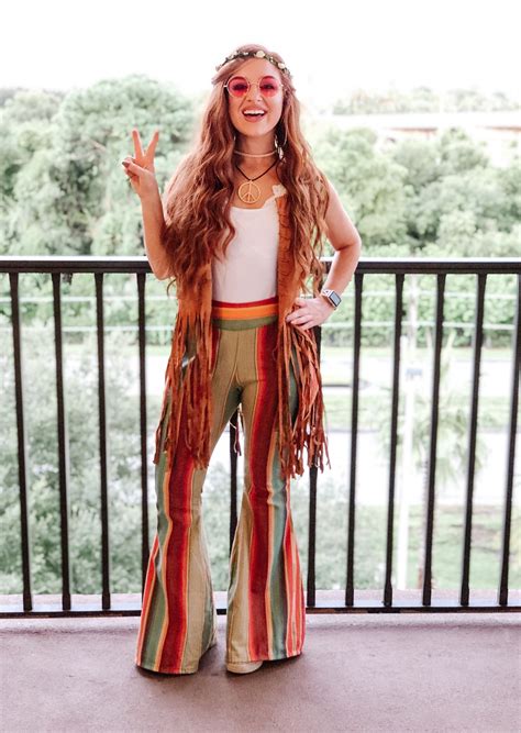 A Woman Standing On A Balcony With Her Hands In The Air And Wearing Colorful Pants