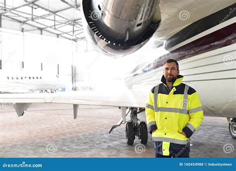 Portrait Of An Aircraft Mechanic In A Hangar With Jets At The Airport