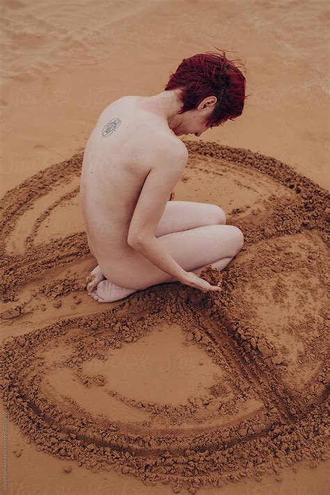 Naked Redhead Girl Drawing Sign On Sand With Her Hands By Stocksy Contributor Liliya