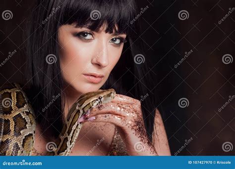 Beautiful And Mysterious Brunette In A Gold Dress And With A Snake