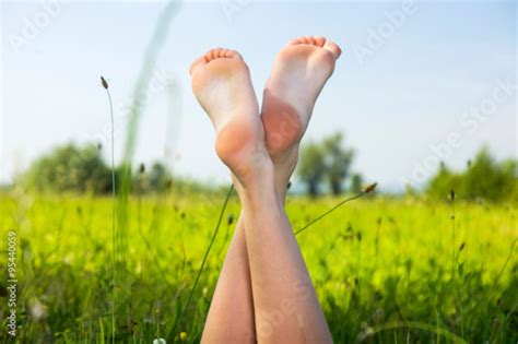 Young Girl Lying In The Grass On Green Meadow Feet Raised Up Body