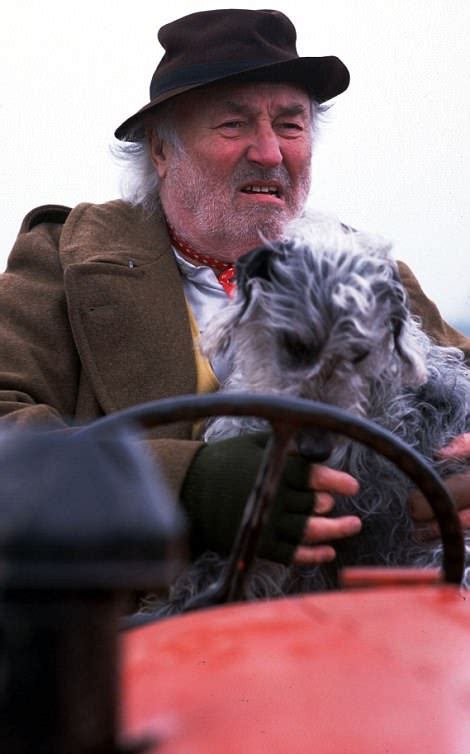 An Old Man Holding A Small Dog In His Lap While Driving A Red Car On