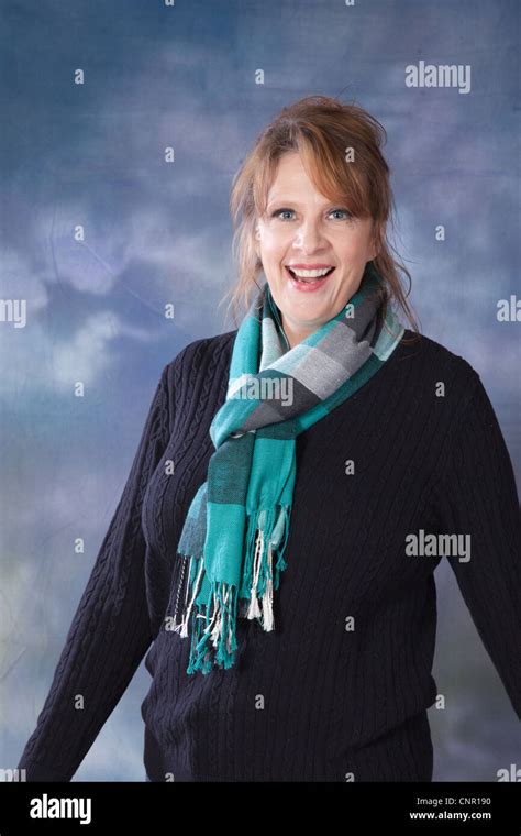 lovely mature caucasian woman in a sweater and scarf smiling at the camera with happy