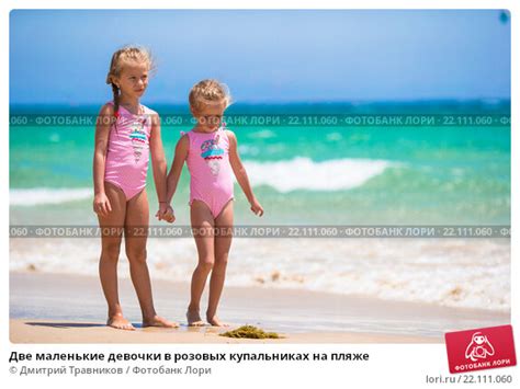 Две маленькие девочки в розовых купальниках на пляже год Редакционное фото
