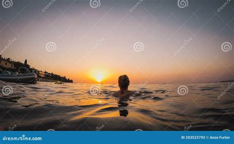 Back View Of A Woman Swimming Towards The Sunset In The Sea Romantic