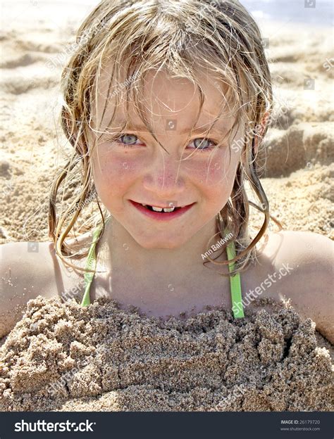 Portrait Of Cute Little Girl On The Beach Buried Up To Her Neck In