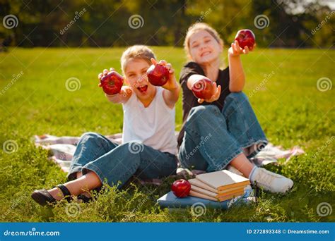 Classmates Two Girls Play With Red Apples On Green Grass In Park Focus