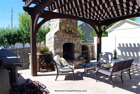 An Outdoor Fireplace And Seating Area In A Backyard With Wood Pergolan