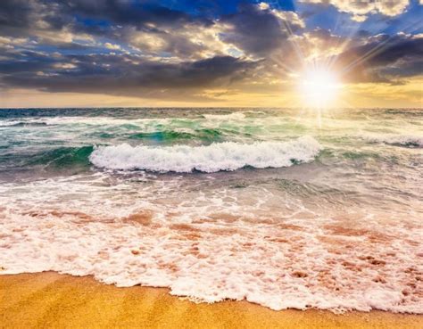 • waves crashing at a calm sea beach. sea waves crashing on sandy beach at sunset — Stock Photo ...