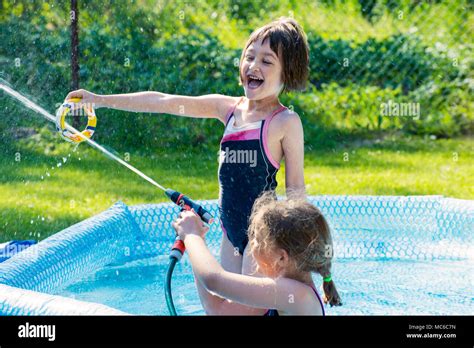 zwei mädchen spaß im pool im freien spiel mit dem wasserschlauch stockfotografie alamy