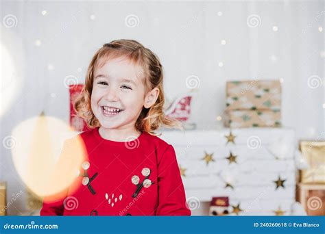 Portrait Of Happy Little Girl At Home Wearing Red Christmas Dress At