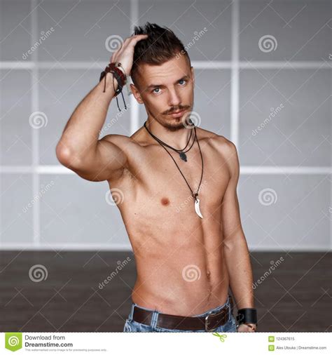Handsome Man With A Naked Torso And Hairstyle Near The Wall Stock
