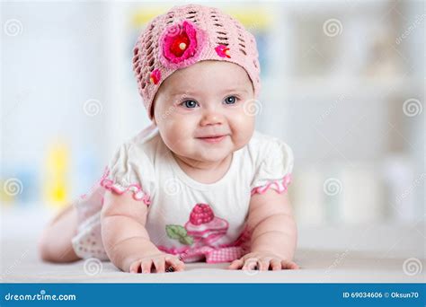 Smiling Baby Girl Lying On Her Belly In Nursery Room Stock Photo