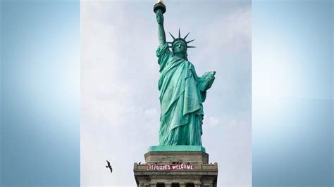 refugees welcome banner unfurled on statue of liberty pedestal