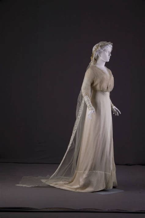 A White Dress And Veil On Display In A Dark Room