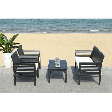 Four Chairs And A Table On The Beach Near The Waters Edge With A