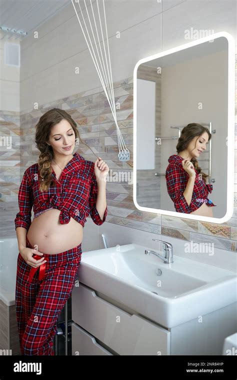 A Pregnant Happy Smilingwoman In The Bathroom Female Dressed In Red