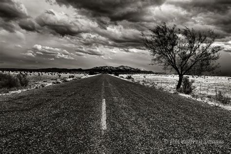Black And White Image Of A Long Straight Rough Blacktop