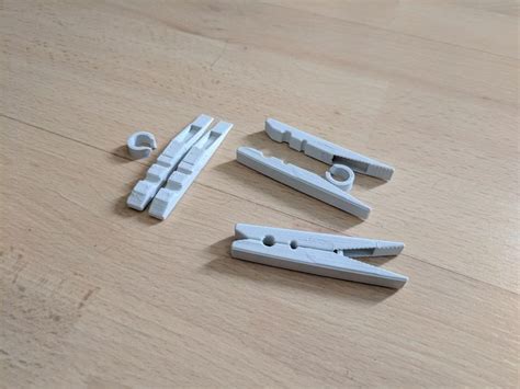 four pieces of metal sitting on top of a wooden table next to scissors and clips