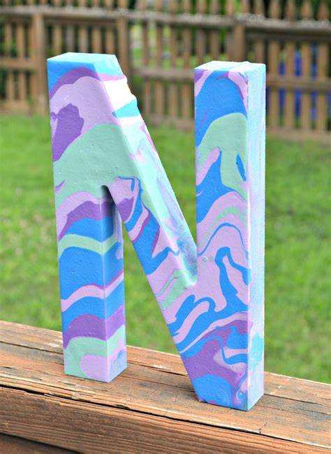 The Letter N Is Painted In Blue Pink And Green Camouflage Print With A