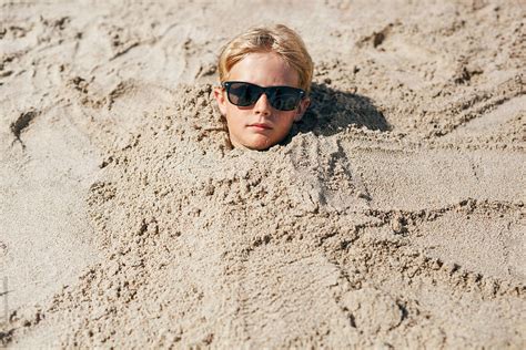 Childs Head Poking Out Of The Sand On The Beach By Stocksy