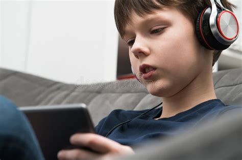 Calm Concentrated Little Boy In Headphones Watching Movies And Listen