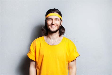 Portrait Of Young Smiling Guy In Yellow Shirt On Background Of Grey