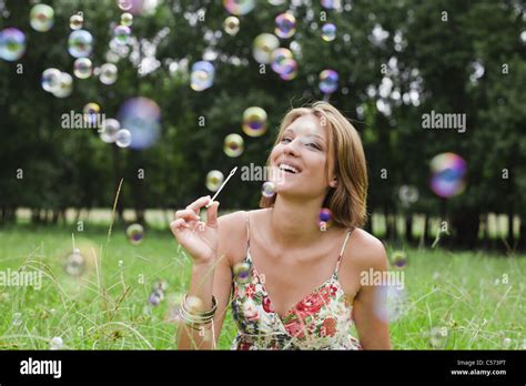 Woman Blowing Bubbles In Field Stock Photo Alamy