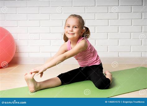 Cheerful Little Girl Doing Sports Exercises On The Mat At Home