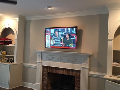 We limited the disturbance in the living room by cutting new conduit pathways into the rear of the brick wall, which happened to be the study. TV Wall Mounting Charlotte NC: TV Mounted on Brick Fireplace
