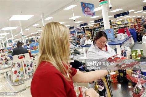 A Tesco employee scans a customer's purchases at a check out desk