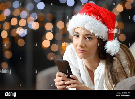 frustrated woman holding a phone on christmas lying on a couch in the living room at home stock