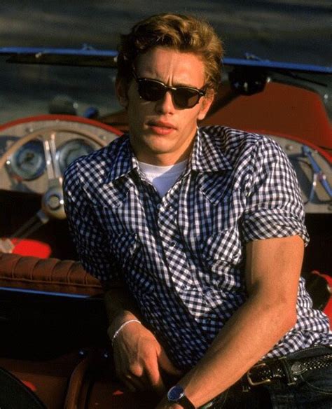 A Man Sitting On Top Of A Red Car Wearing Sunglasses And A Checkered Shirt